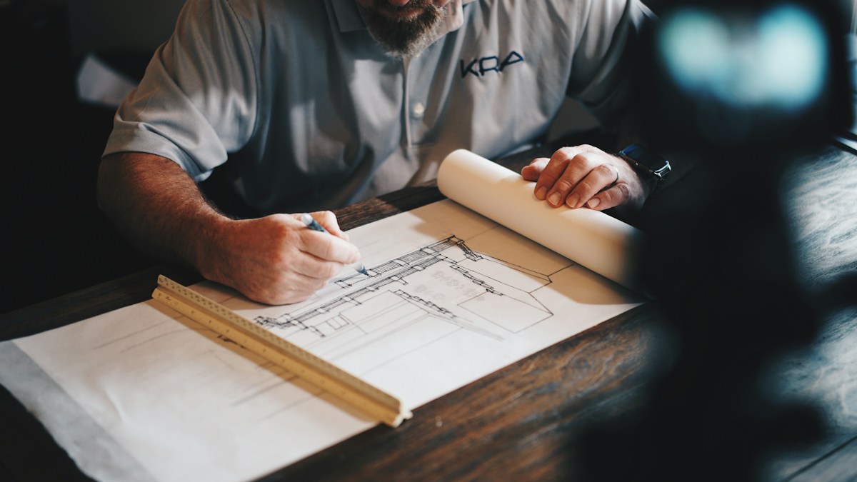 Architect drawing a building plan with drafting tools