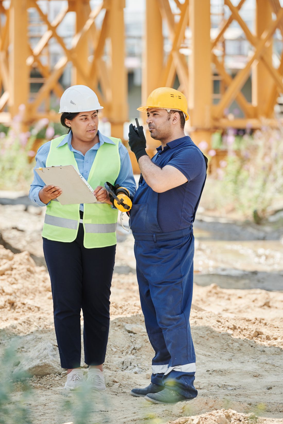 Two construction professionals coordinating site work with a clipboard and radio