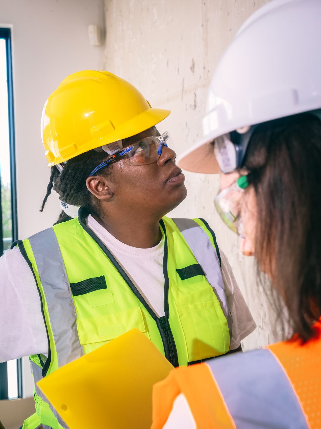 Two workers in hard hats and safety glasses reviewing an unfinished interior